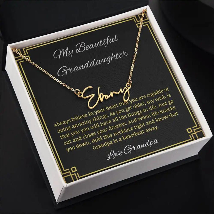 Signature Name Necklace with a yellow gold finish on a to granddaughter from grandpa greeting card in a two-tone box angled to the right