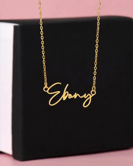 gold signature style name necklace on top of soft box