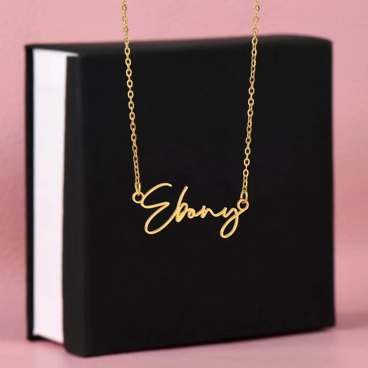 gold signature style name necklace on top of soft box