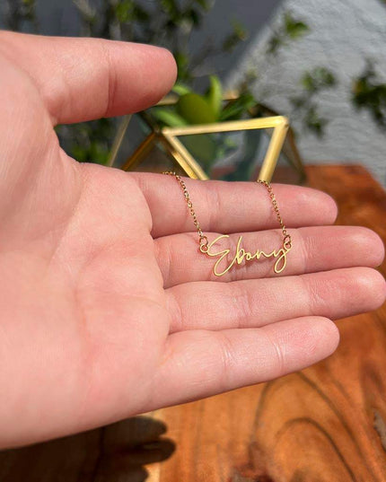 yellow gold signature name necklace in a model's hand