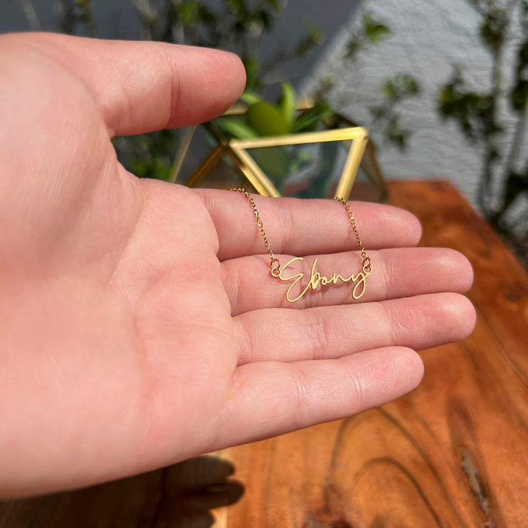yellow gold signature name necklace in a model's hand