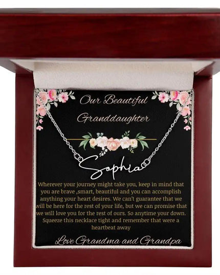 Signature Name Necklace with a polished stainless steel finish and a to granddaughter from grandma and grandpa greeting card in a mahogany box up close