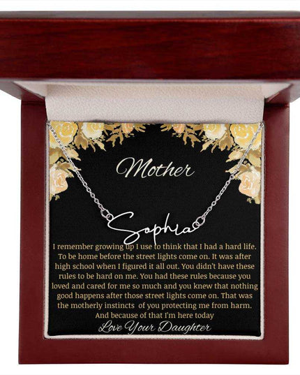 A polished stainless-steel signature name necklace in a mahogany box.