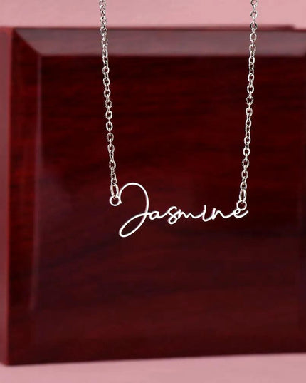 polished-stainless signature style name necklace on top of mahogany box