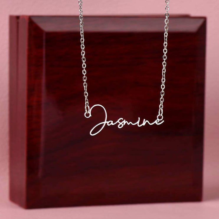 stainless-steel signature name necklace on top of a closed luxury box