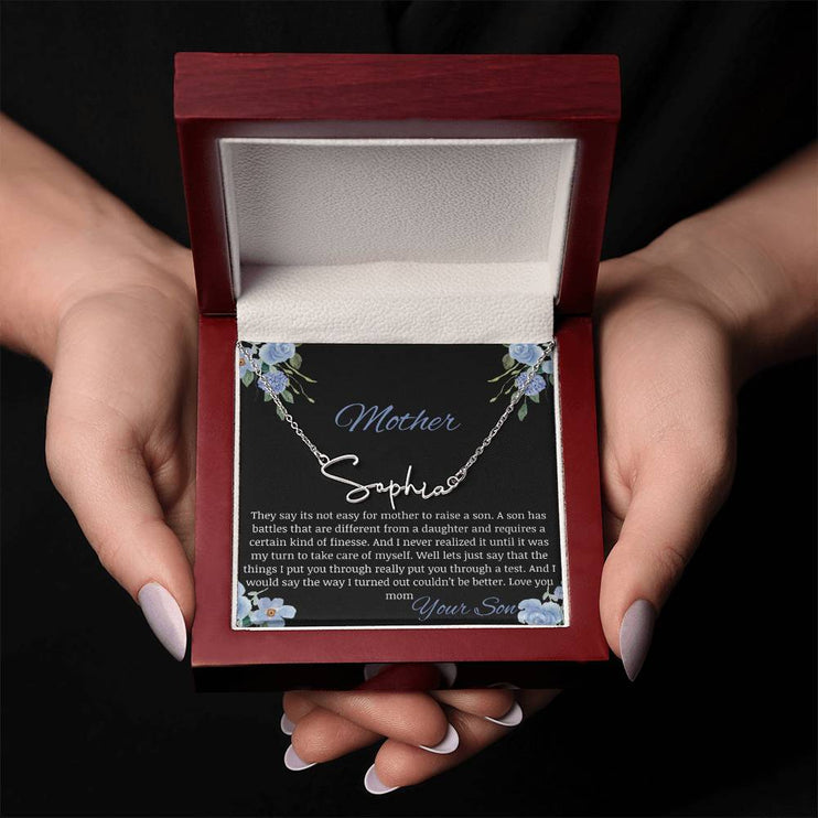 A polished stainless-steel signature name necklace in a mahogany box in a models hands