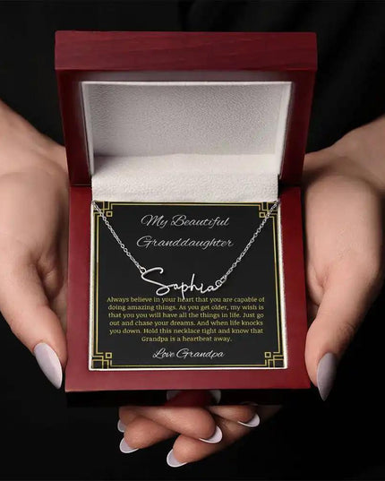 Signature Name Necklace with a polished stainless-steel finish on a to granddaughter from grandpa greeting card in a mahogany box in a models hands