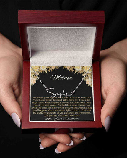 A polished stainless-steel signature name necklace in a mahogany box held by a model