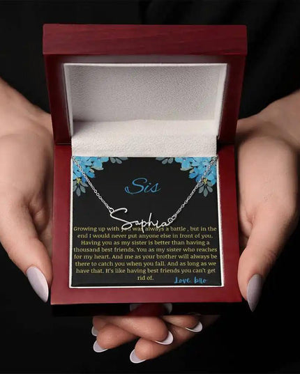 Signature Name Necklace with a polished stainless-steel charm on a to sis from bro greeting card in a mahogany box in a models hand