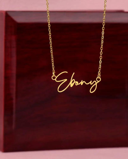 gold signature style name necklace on top of a mahogany box