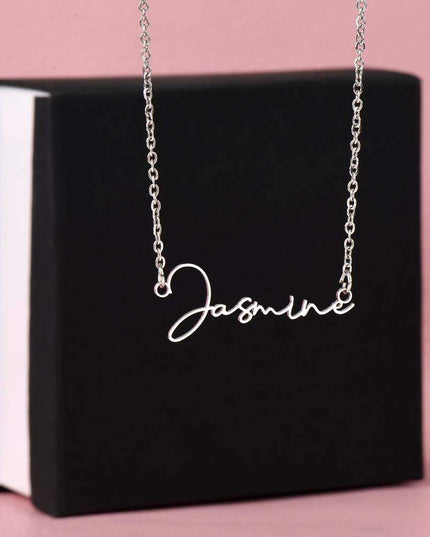 a polished stainless-steel necklace signature name necklace on top a two-tone box