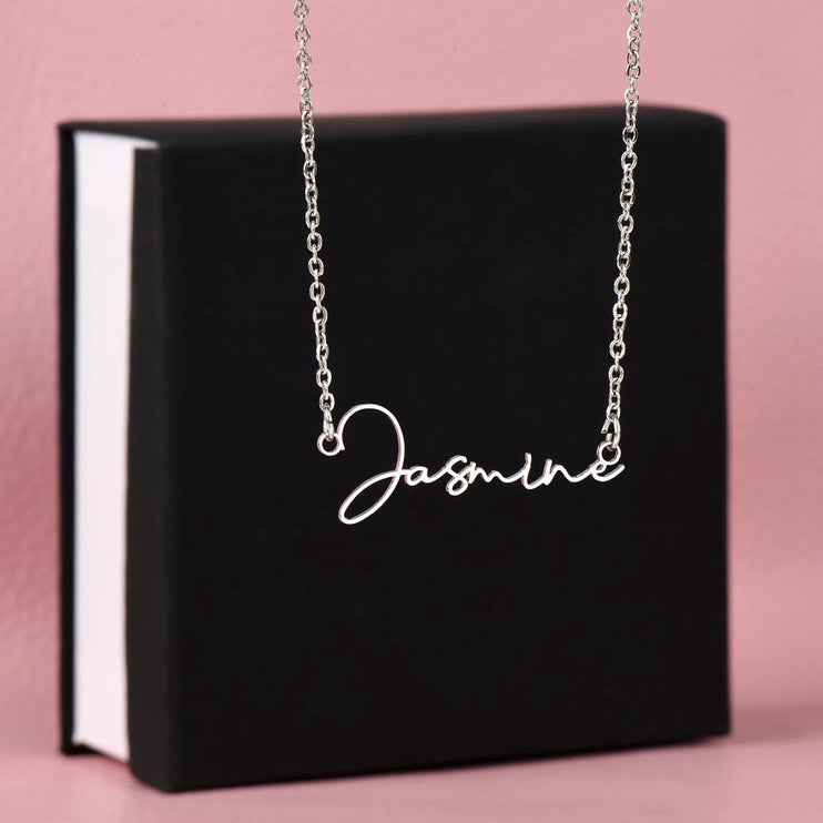 a polished stainless-steel necklace signature name necklace on top a two-tone box