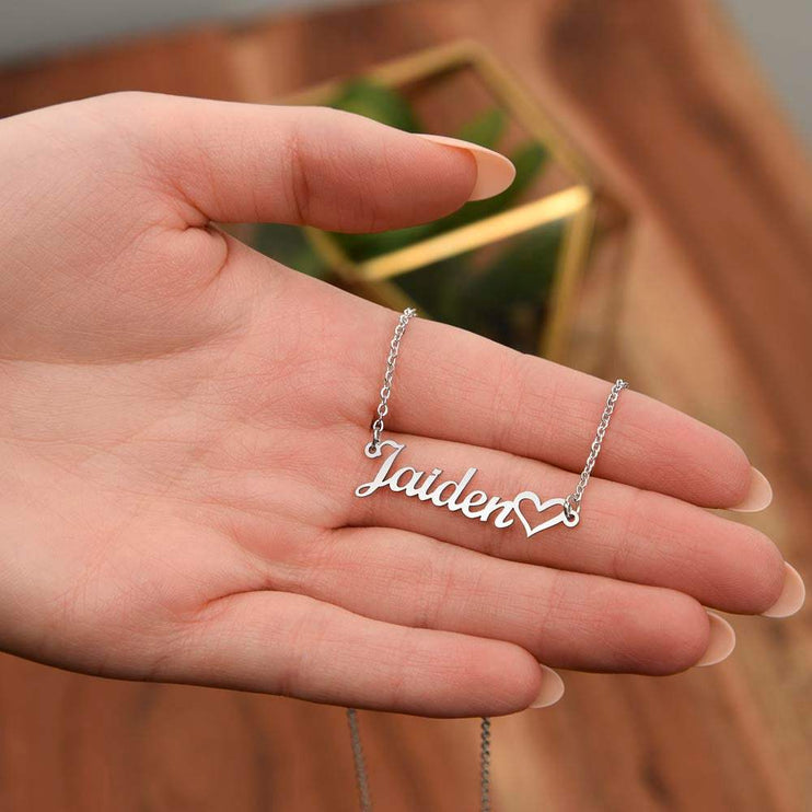 polished stainless-steel name heart necklace in the palm of a model's hands