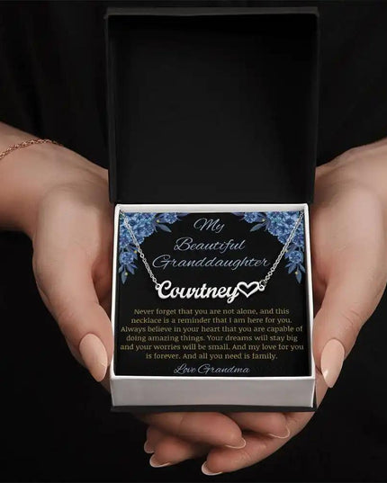 Name Heart Necklace with a polished stainless-steel charm on a to granddaughter from grandma greeting card in a two-tone box in a models hands