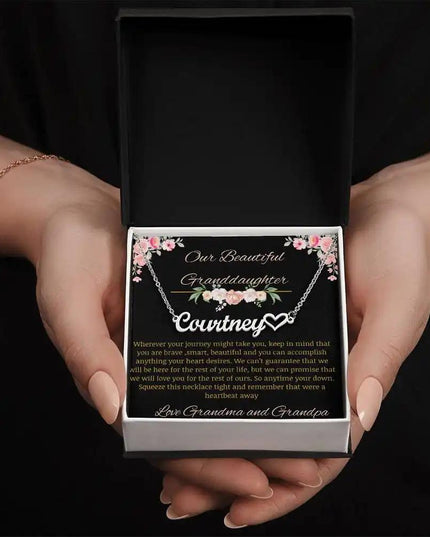 Name Heart Necklace with a polished stainless-steel finish on a to granddaughter from grandma and grandpa greeting card in a two-tone box in a models hands