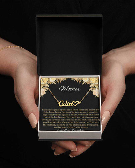 A yellow gold finish name heart necklace in a two-tone box.