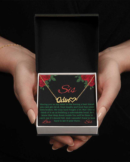 Name Heart Necklace with a yellow gold finish variant on a To Sis from Sis greeting card up close view in the hands of a model.