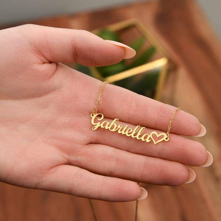 gold name heart necklace in a model's hand