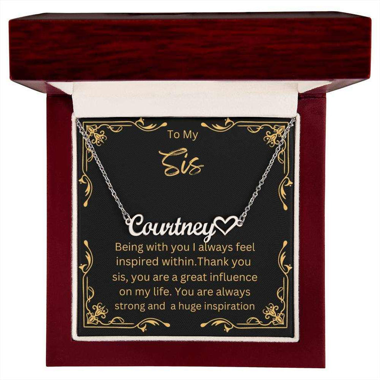 Name Heart Necklace with a polished stainless-steel variant on a To Sis greeting card inside a mahogany box up close view 