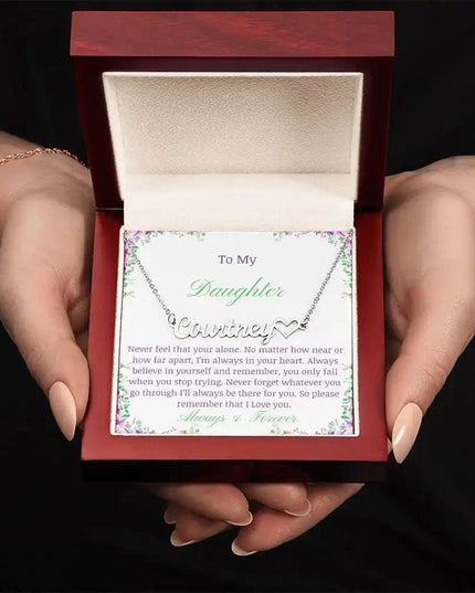 A polished stainless-steel name heart necklace in a mahogany box in models hands