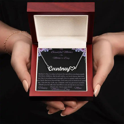 polished stainless-steel name heart necklace in a mahogany box in models hands