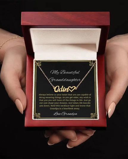 Name Heart Necklace with a yellow gold finish charm on a to granddaughter from grandpa greeting card in a mahogany box in a models hands