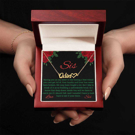 Name Heart Necklace with a yellow gold variant on a To Sis from Sis greeting card inside a mahogany box up close view in the hands of a model.