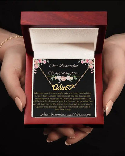 Name Heart Necklace with a yellow gold finish on a to granddaughter from grandma and grandpa greeting card in a mahogany box in a models hands