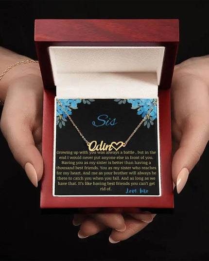 Name Heart Necklace with a yellow gold finish charm with a to sis from bro greeting card in a mahogany box in a models hand