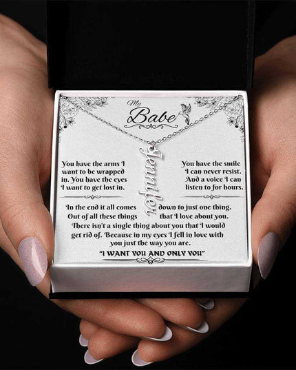 polished stainless-steel vertical name necklace in a soft box in model's hands