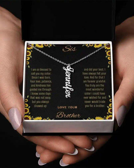 Vertical Name Necklace with a polished stainless-steel charm on a to sis from brother greeting card in a two-tone box and held in a models hands