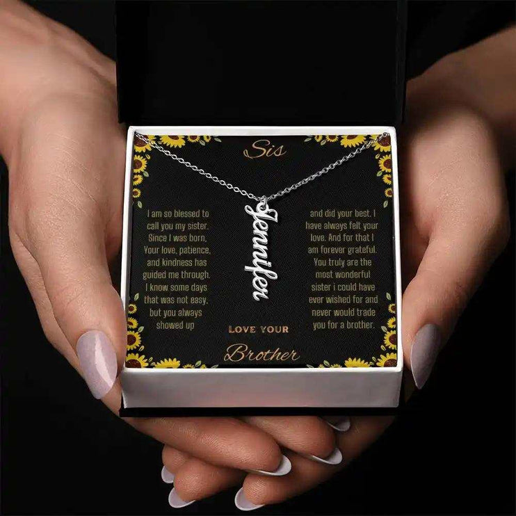 Vertical Name Necklace with a polished stainless-steel charm on a to sis from brother greeting card in a two-tone box and held in a models hands