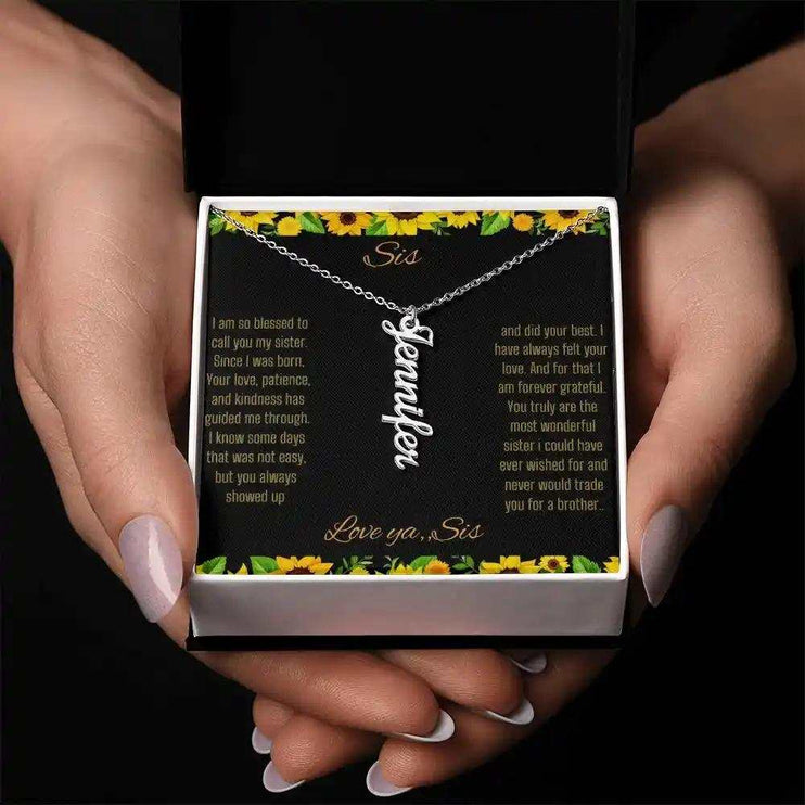 Vertical Name Necklace with a polished stainless-steel finish on a To Sis From Sis greeting card in a models hands
