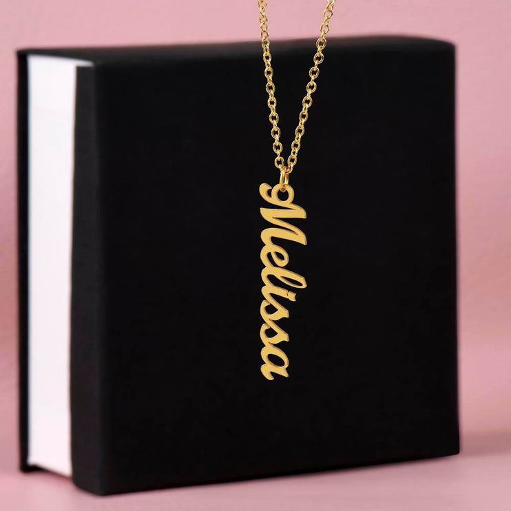 gold vertical name necklace on top of a soft box 