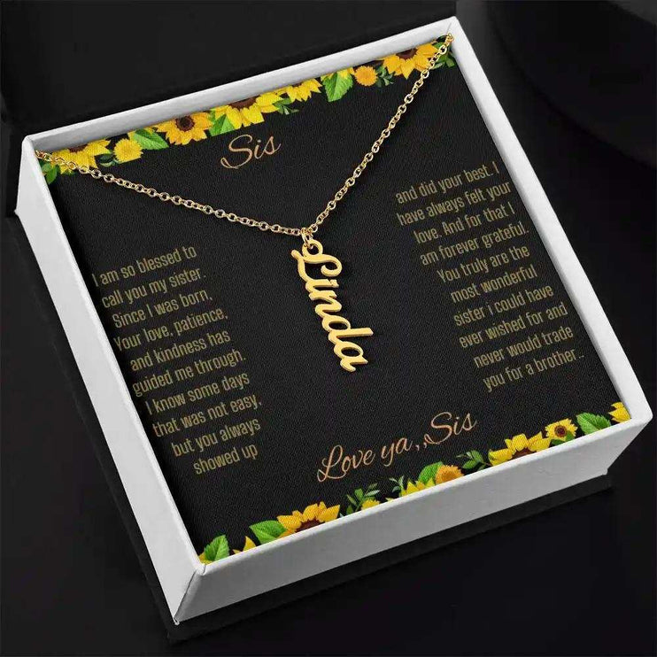Vertical Name Necklace with a yellow gold finish on a To Sis From Sis greeting card inside a two-tone box close up angled slightly to right