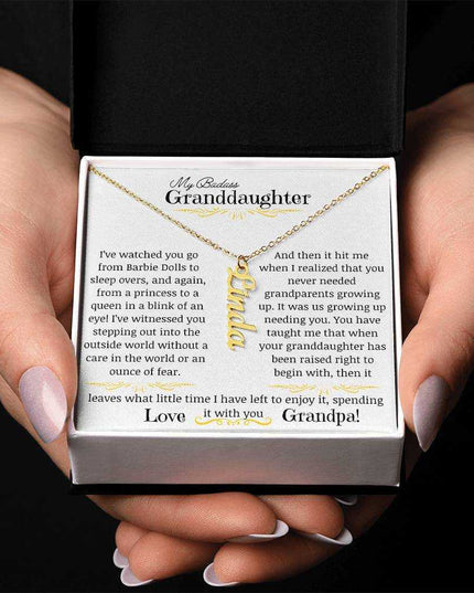 a yellow gold vertical name necklace up close in a models hands.