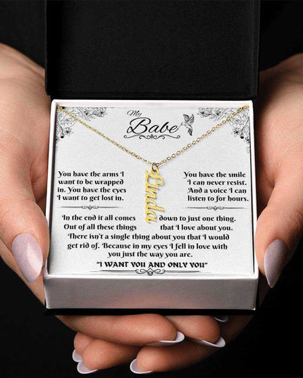 yellow gold vertical name necklace in a soft box in model's hands