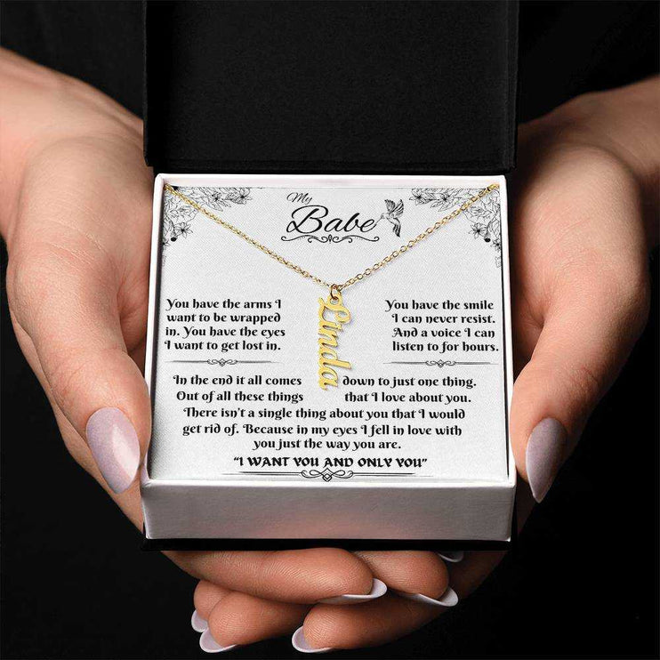 yellow gold vertical name necklace in a soft box in model's hands