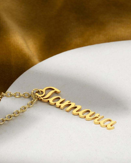 yellow gold vertical name necklace on a white table