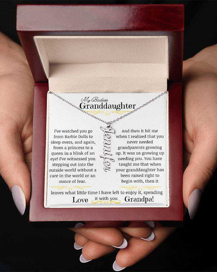 a polished stainless-steel vertical name necklace in a mahogany box in a models hands.