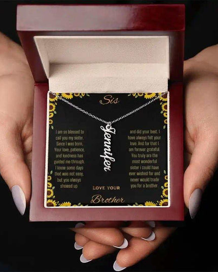 Vertical Name Necklace with a polished stainless-steel charm on a to sis from brother greeting card in a mahogany box in a models hands
