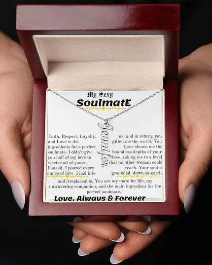 a polished stainless steel vertical name necklace in a mahogany box in hands