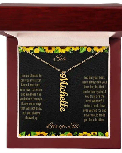 Vertical Name Necklace with a yellow gold finish on a To Sis From Sis greeting card inside a mahogany box close up 