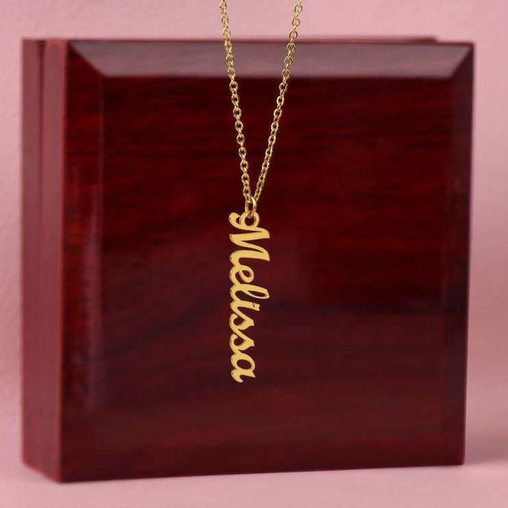 gold vertical name necklace on top of an upright luxury box