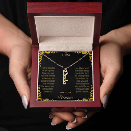 Vertical Name Necklace with a yellow gold finish charm on a to sis from brother greeting card in a mahogany box in a models hands