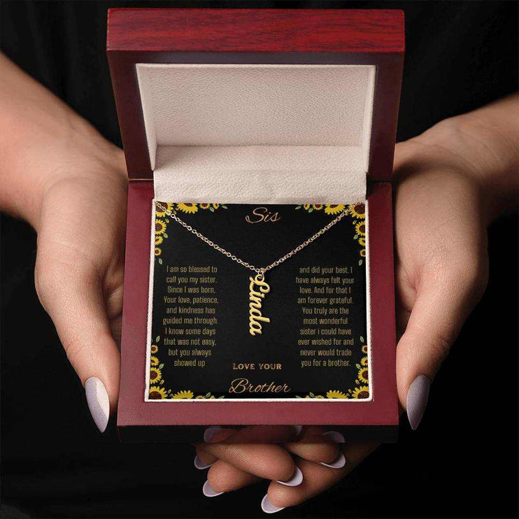 Vertical Name Necklace with a yellow gold finish charm on a to sis from brother greeting card in a mahogany box in a models hands