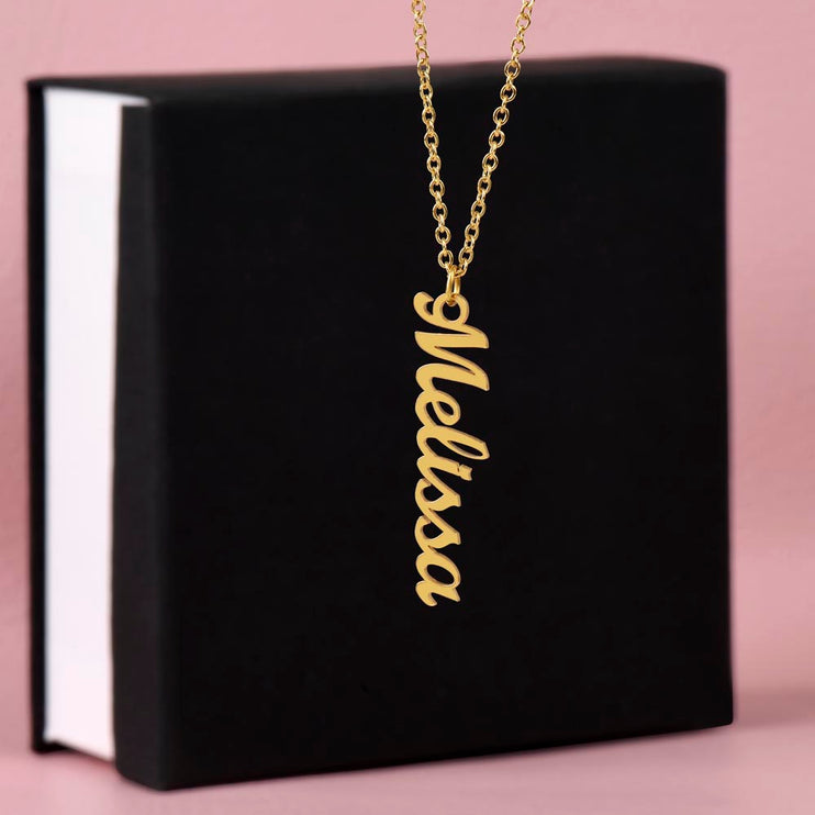 a yellow gold vertical name necklace on top of a two-tone box