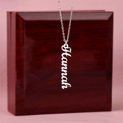 a polished stainless-steel  vertical name necklace on top of a mahogany box