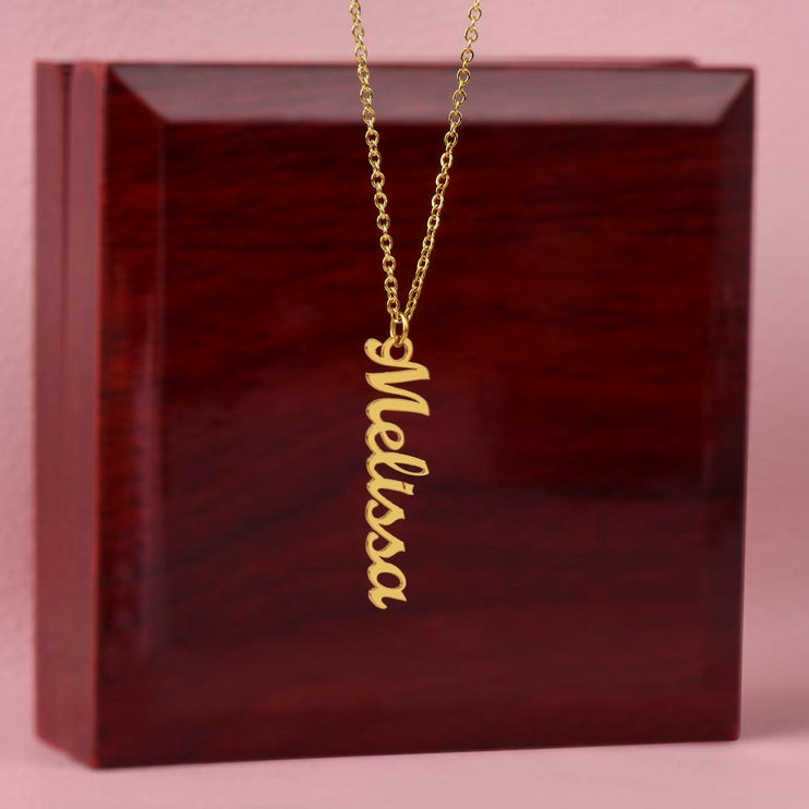 a vertical name necklace on top of a mahogany box
