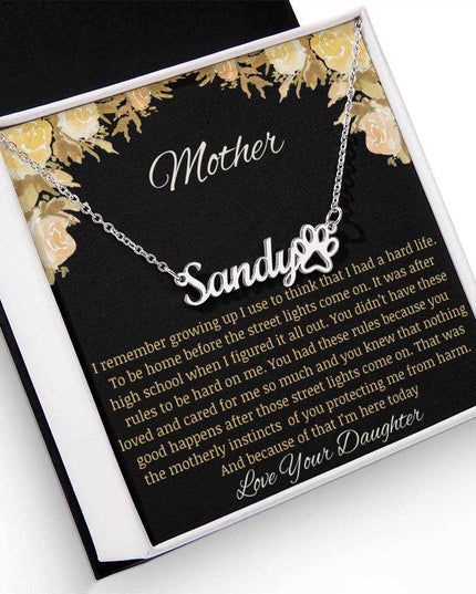 A polished stainless-steel pet name paw print necklace in a two-tone box.